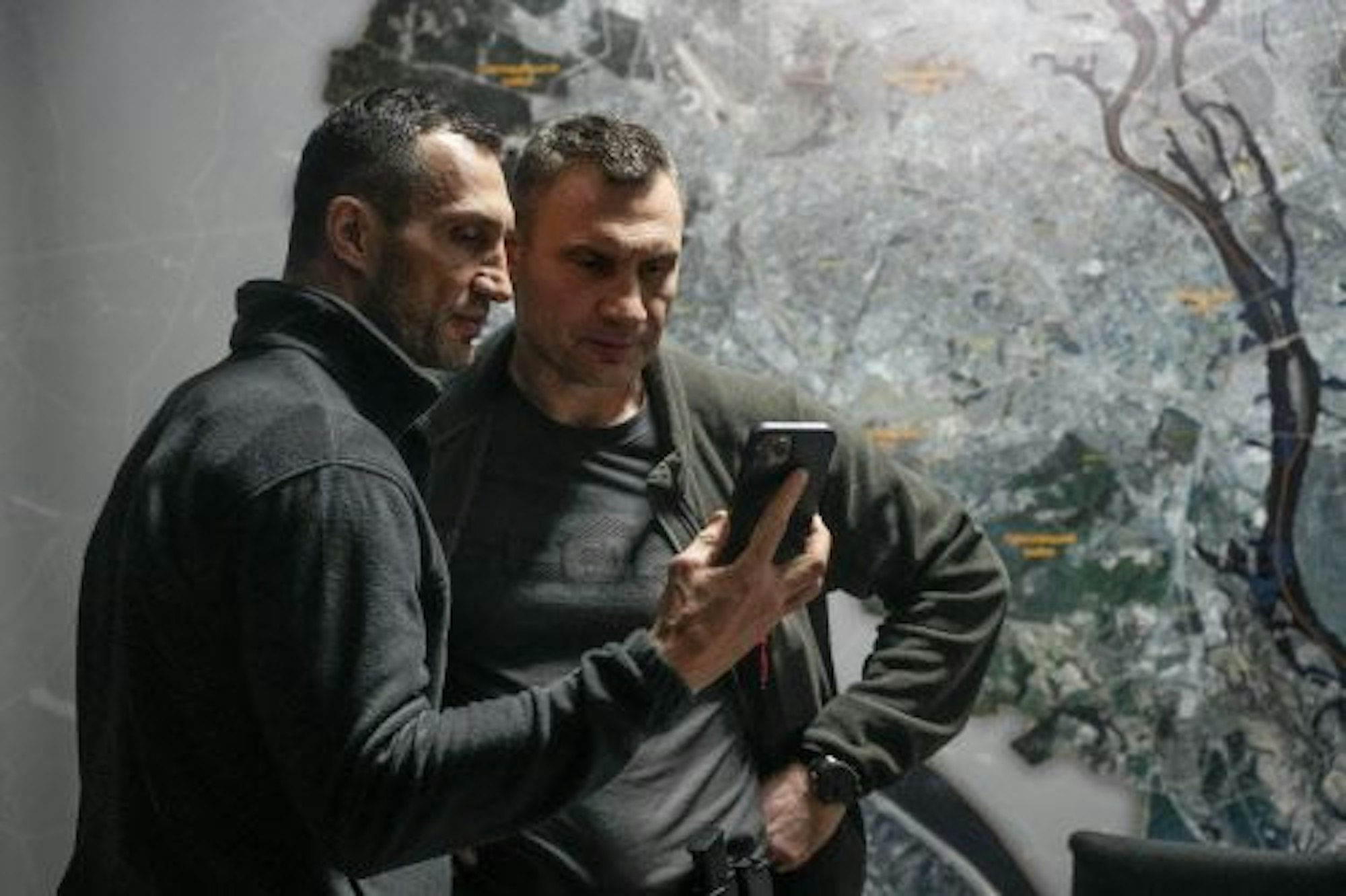Vitali und Waldimir Klitschko schauen auf ein Smartphone.