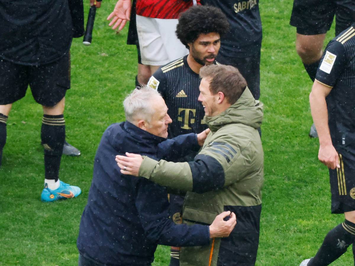 Freiburgs Trainer Christian Streich (l) und Münchens Cheftrainer Julian Nagelsmann (r) verabschieden sich nach Spielende voneinander, dahinter geht Münchens Serge Gnabry.