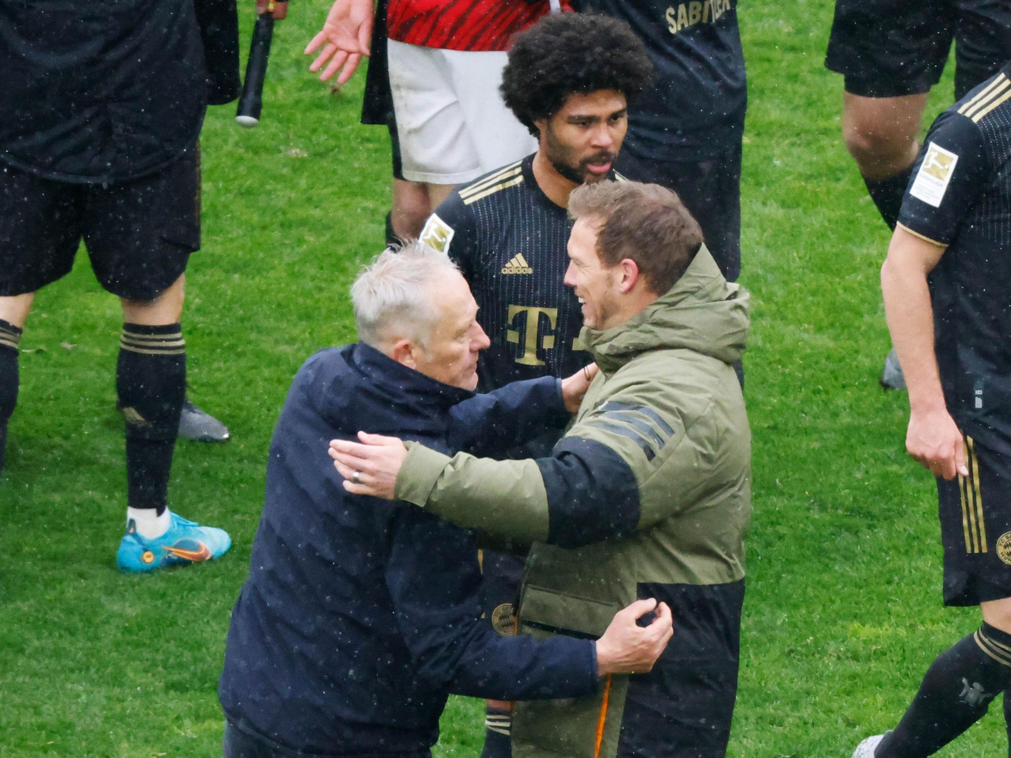 Freiburgs Trainer Christian Streich (l) und Münchens Cheftrainer Julian Nagelsmann (r) verabschieden sich nach Spielende voneinander, dahinter geht Münchens Serge Gnabry.