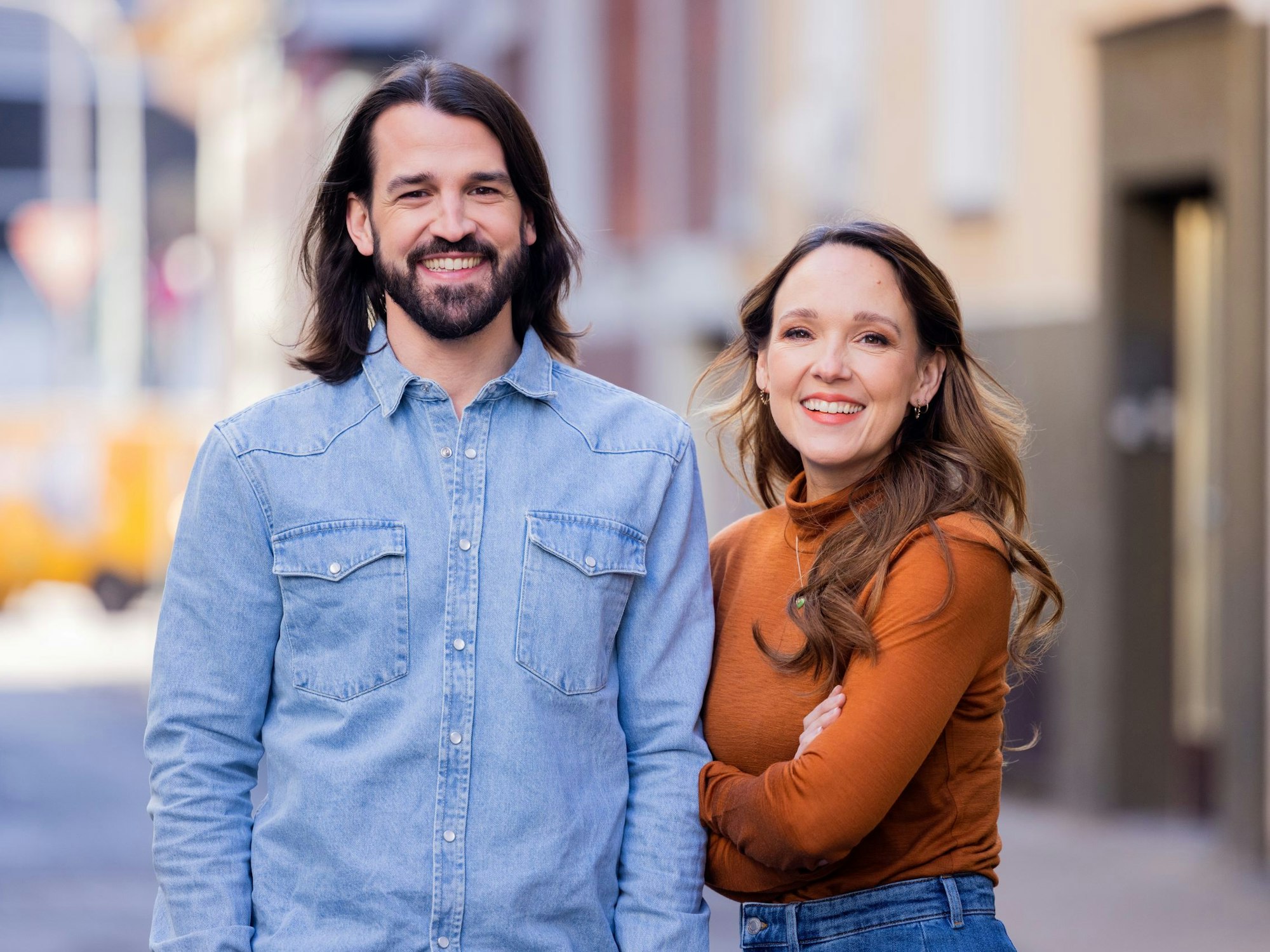 Carolin Kebekus, Comedian, und ihr Bruder David Kebekus, Autor, stehen in einer Gasse.