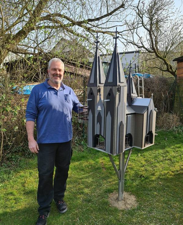 Frank Hirschfeld steht neben seinem Vogelhaus im Garten.