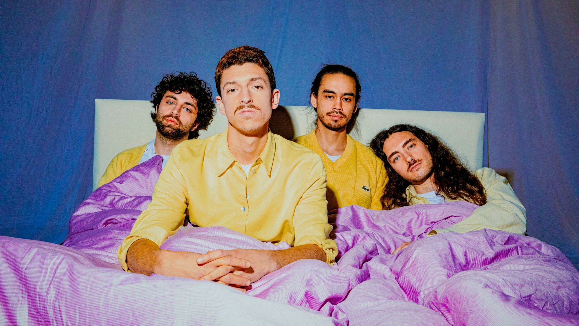 Die Bandmitglieder von Tigermilch posieren im Bett. Mit ihrem eigenen, speziellen Stil erobern die Kölner die Musikwelt.