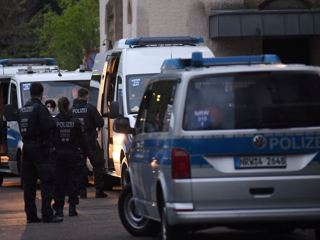 Polizeifahrzeuge und Einsatzkräfte stehen vor einem Kölner Flüchtlingsheim.