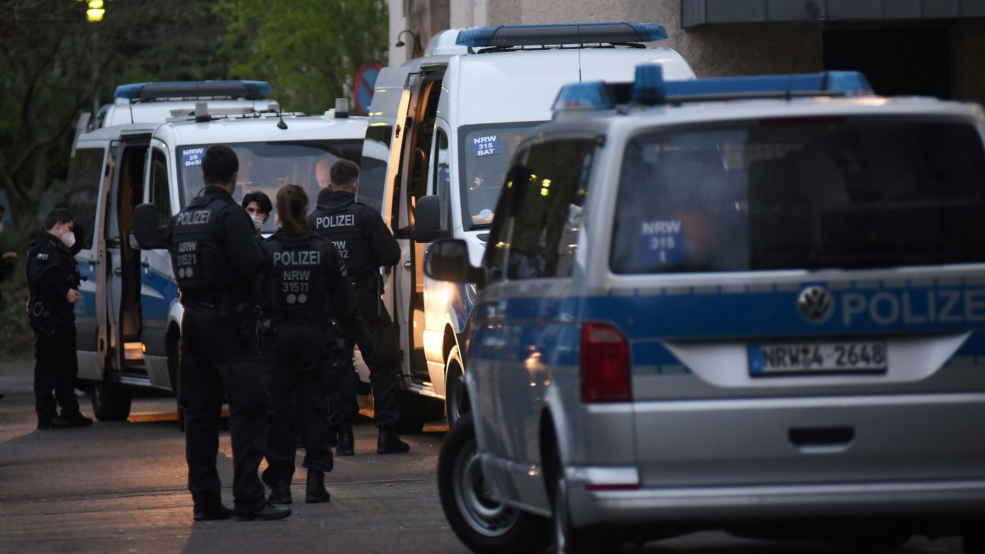 Fahrzeuge der Polizei sowie mehrere Einsatzkräfte stehen auf einer Straße.