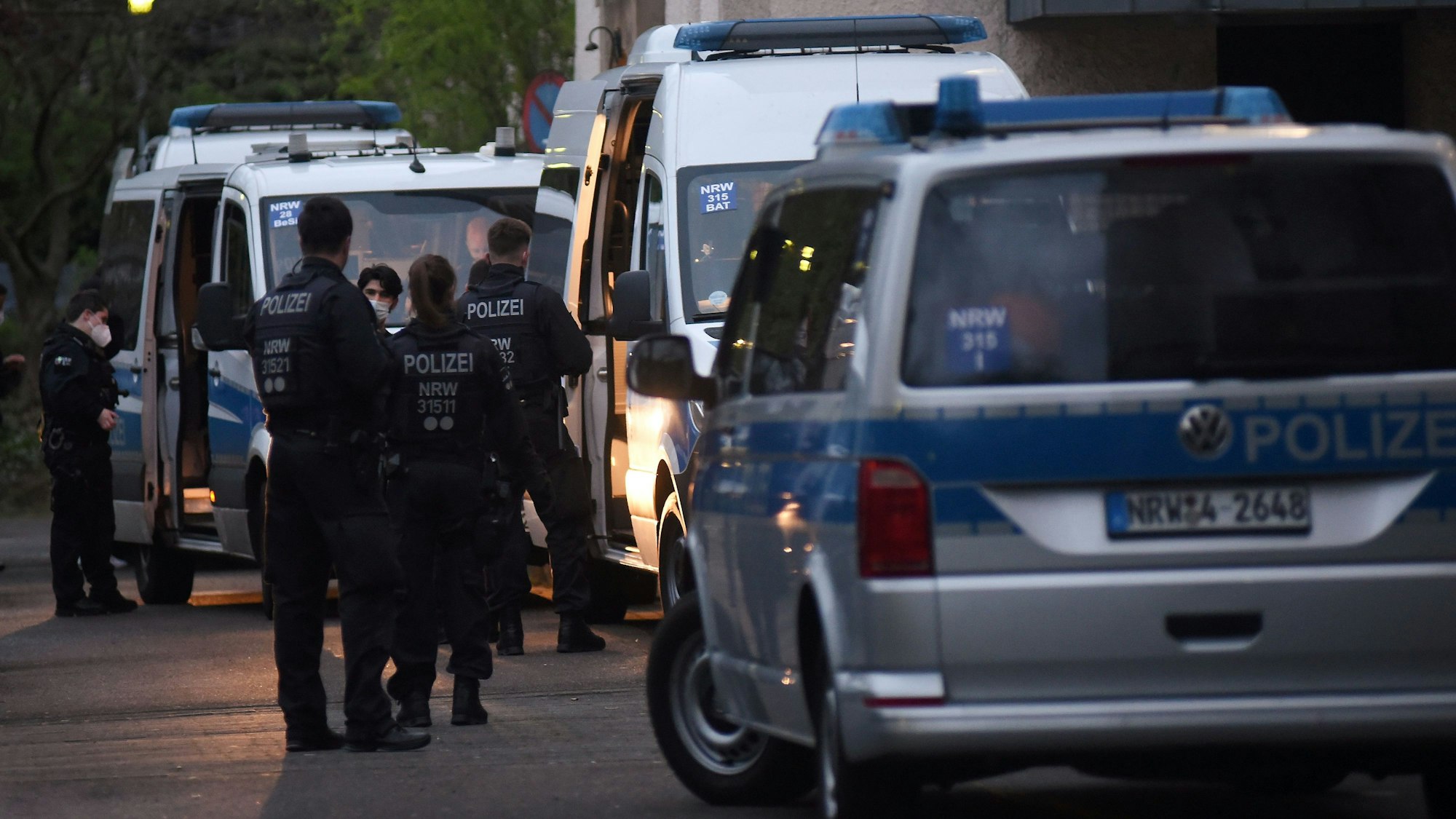 Polizeifahrzeuge und Einsatzkräfte stehen vor einem Gebäude.
