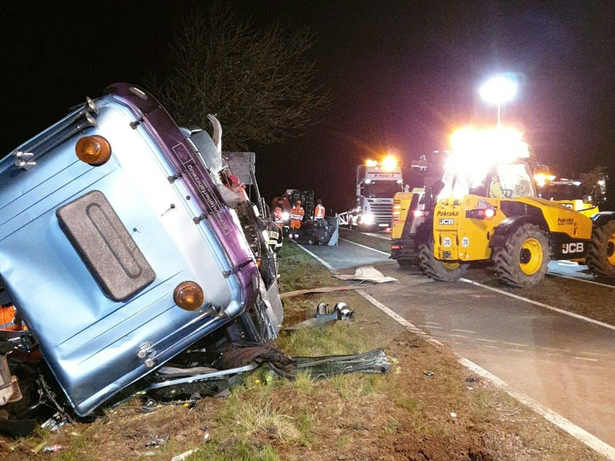 Ein Sattelschlepper samt Anhänger liegen neben der Fahrbahn und werden von einem Bergungsteam aus dem Graben gezogen.