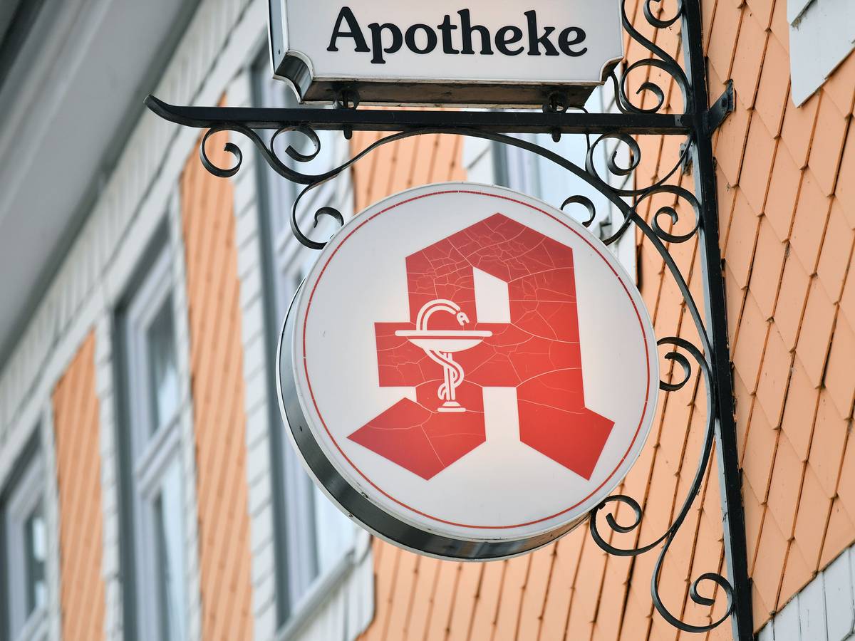 Das Apothekenzeichen hängt an einer Hausfassade.