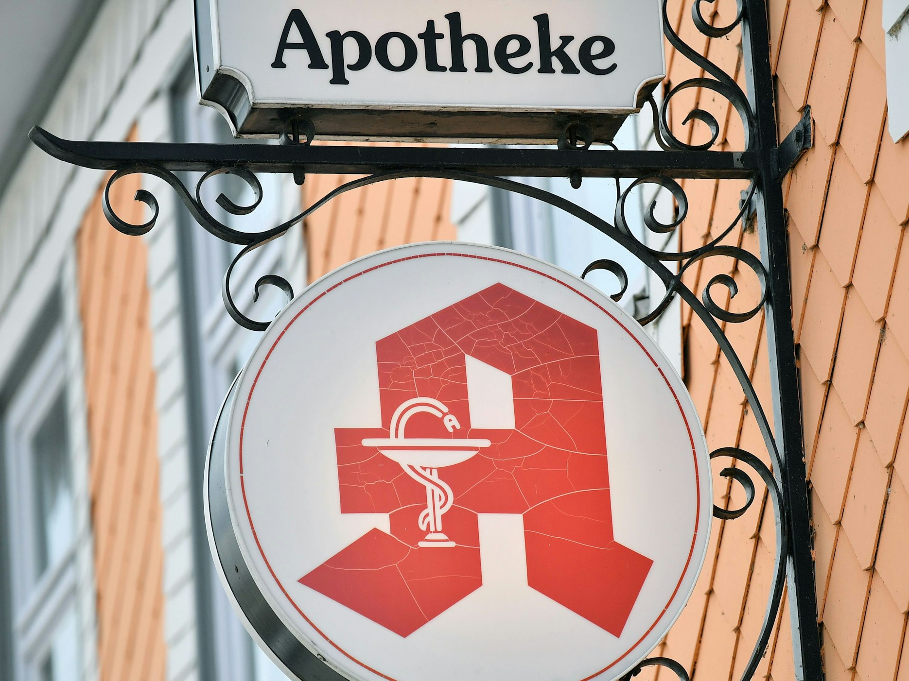 Das Apothekenzeichen hängt an einer Hausfassade.