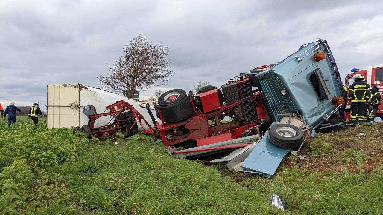 Ein Sattelzug liegt samt Anhänger in einem Feld neben der Straße.