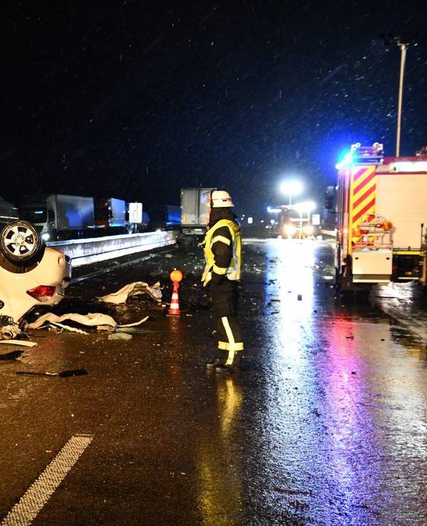 Das Auto eines Geisterfahrers liegt auf dem Dach auf der Fahrbahn der A1 nahe Blankenheim. Einsatzkräfte stehen in der Nähe.