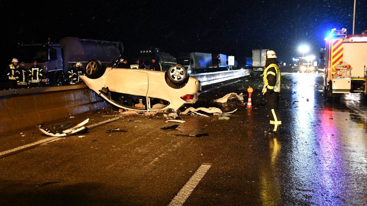 Das Auto eines Geisterfahrers liegt auf dem Dach auf der Fahrbahn der A1 nahe Blankenheim. Einsatzkräfte stehen in der Nähe.