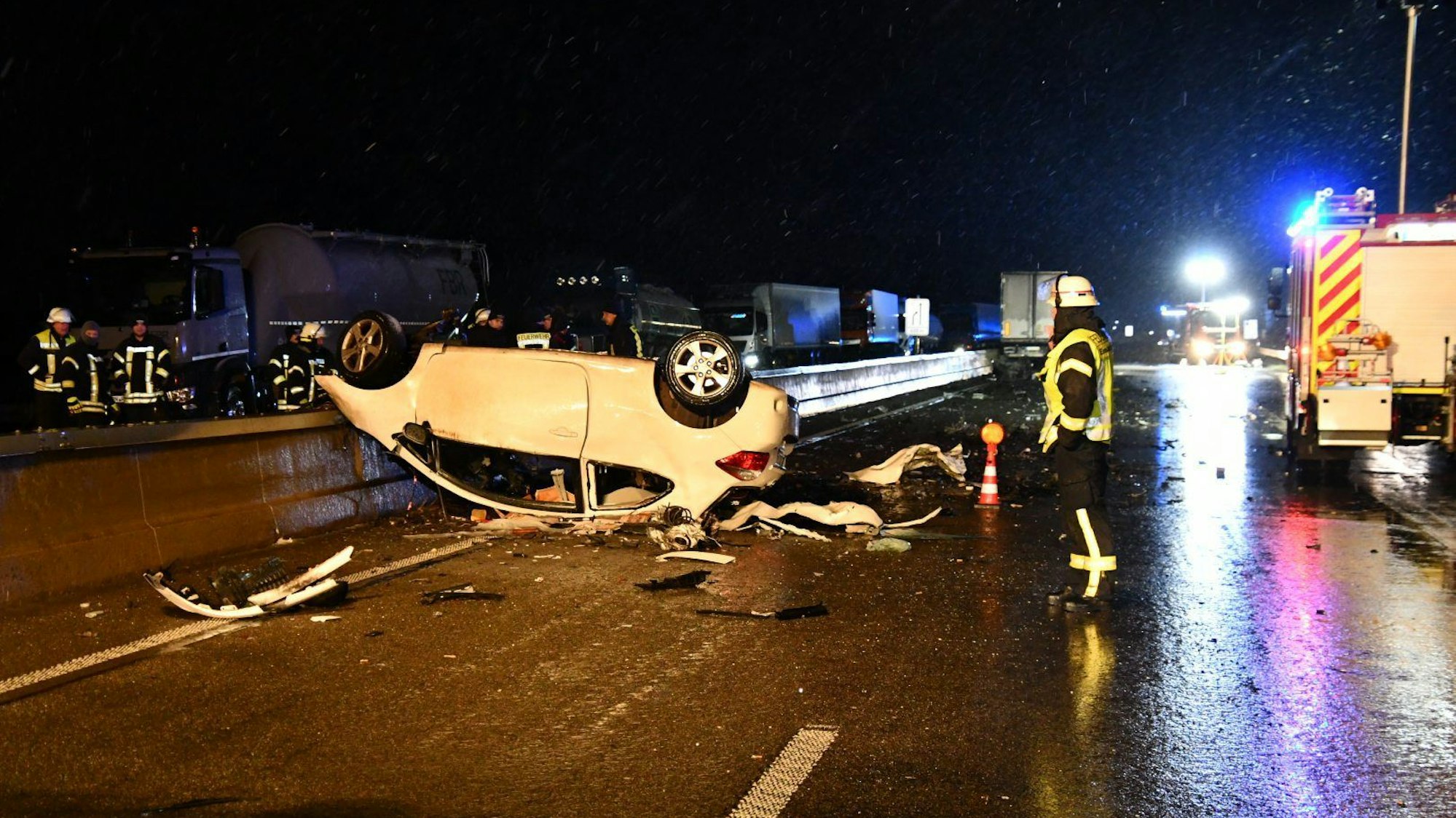 Das Auto eines Geisterfahrers liegt auf dem Dach auf der Fahrbahn der A1 nahe Blankenheim. Einsatzkräfte stehen in der Nähe.