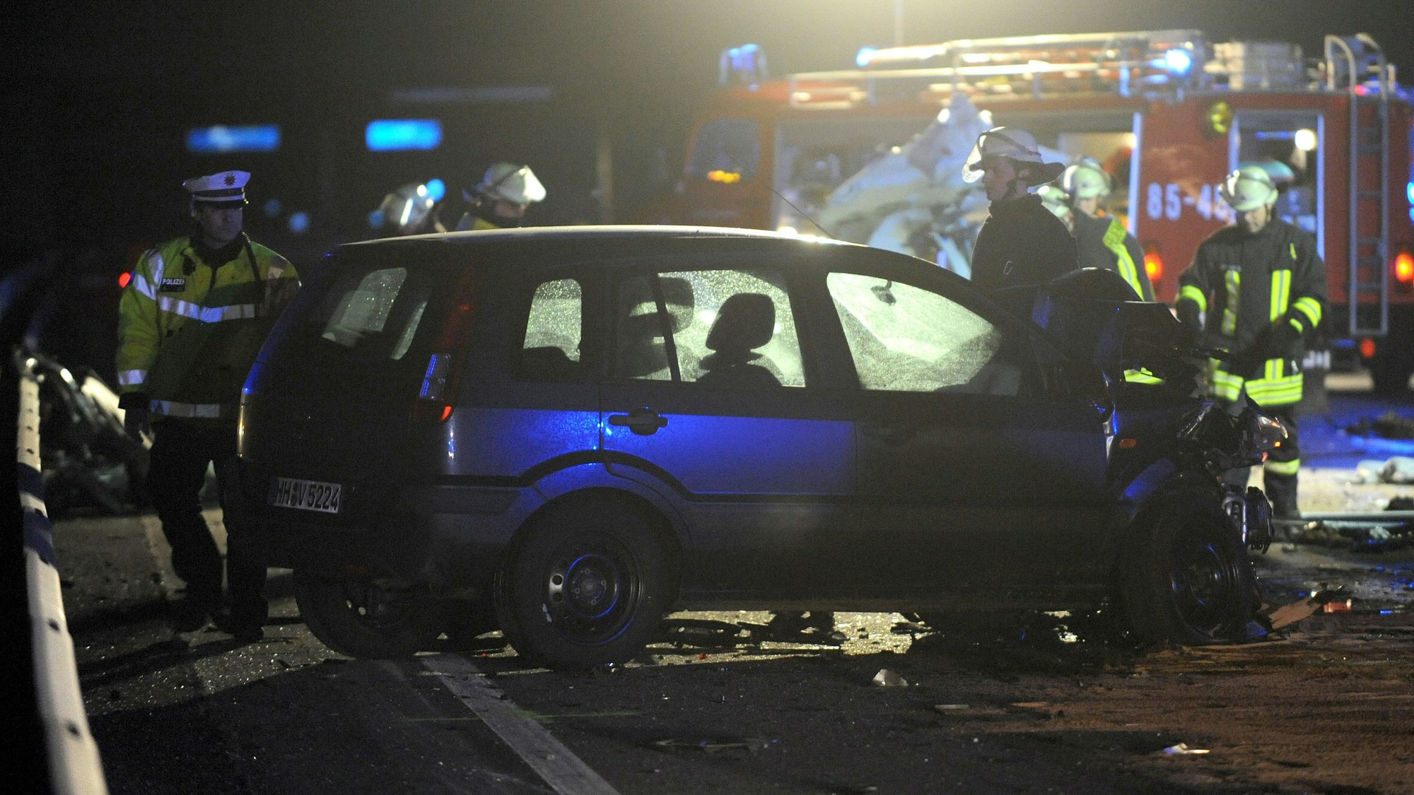 Einsatzkräfte stehen an einem Auto, das auf der Autobahn verunglückt ist.