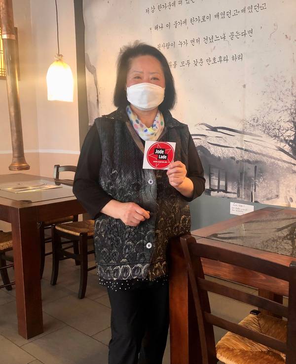 Die Inhaberin des koreanischen Restaurants Nakwon, Joeng Sook Choe Lee, hält das Jode Lade-Gütesiegel in die Kamera.
