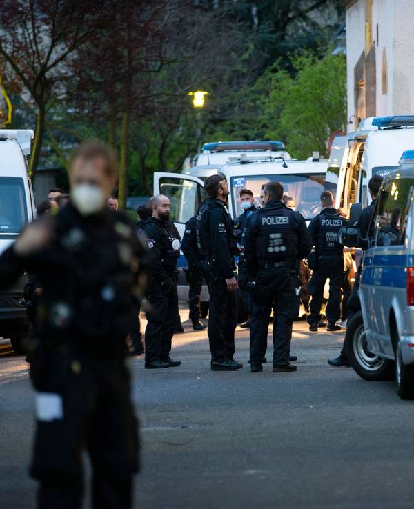 Polizeikräfte stehen vor mehreren Polizeiautos.