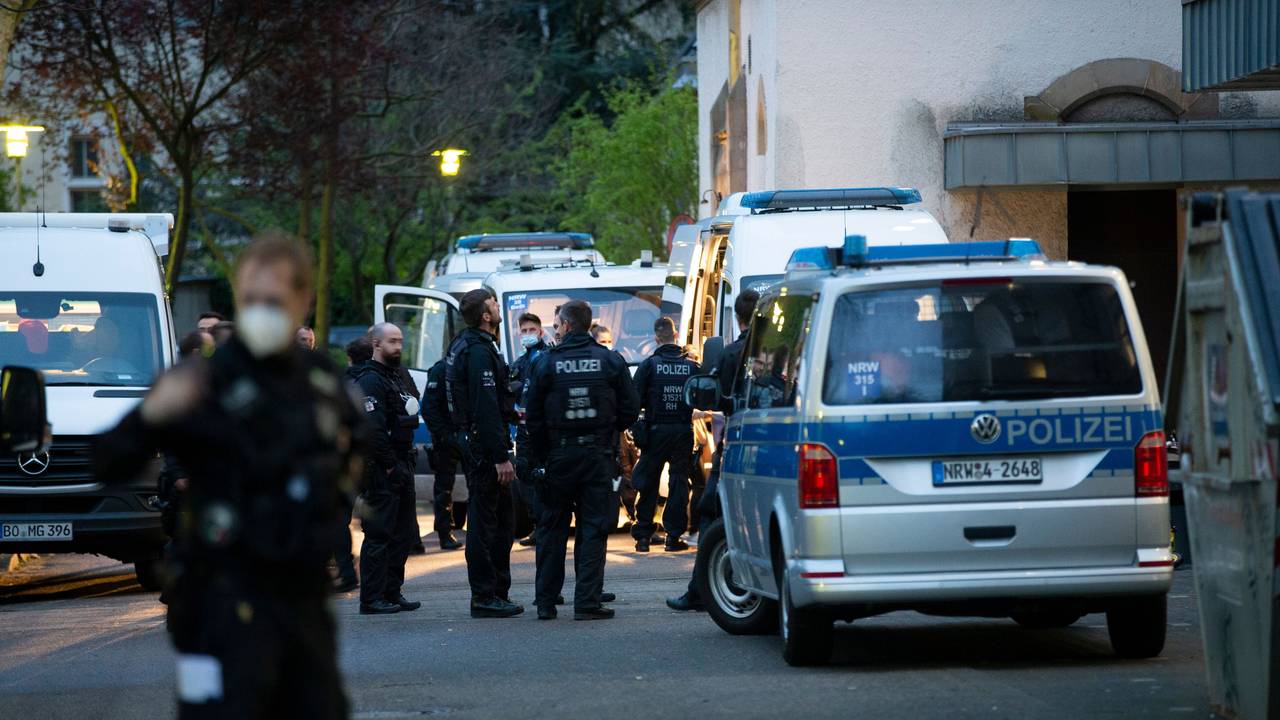 Polizeikräfte stehen vor mehreren Polizeiautos.