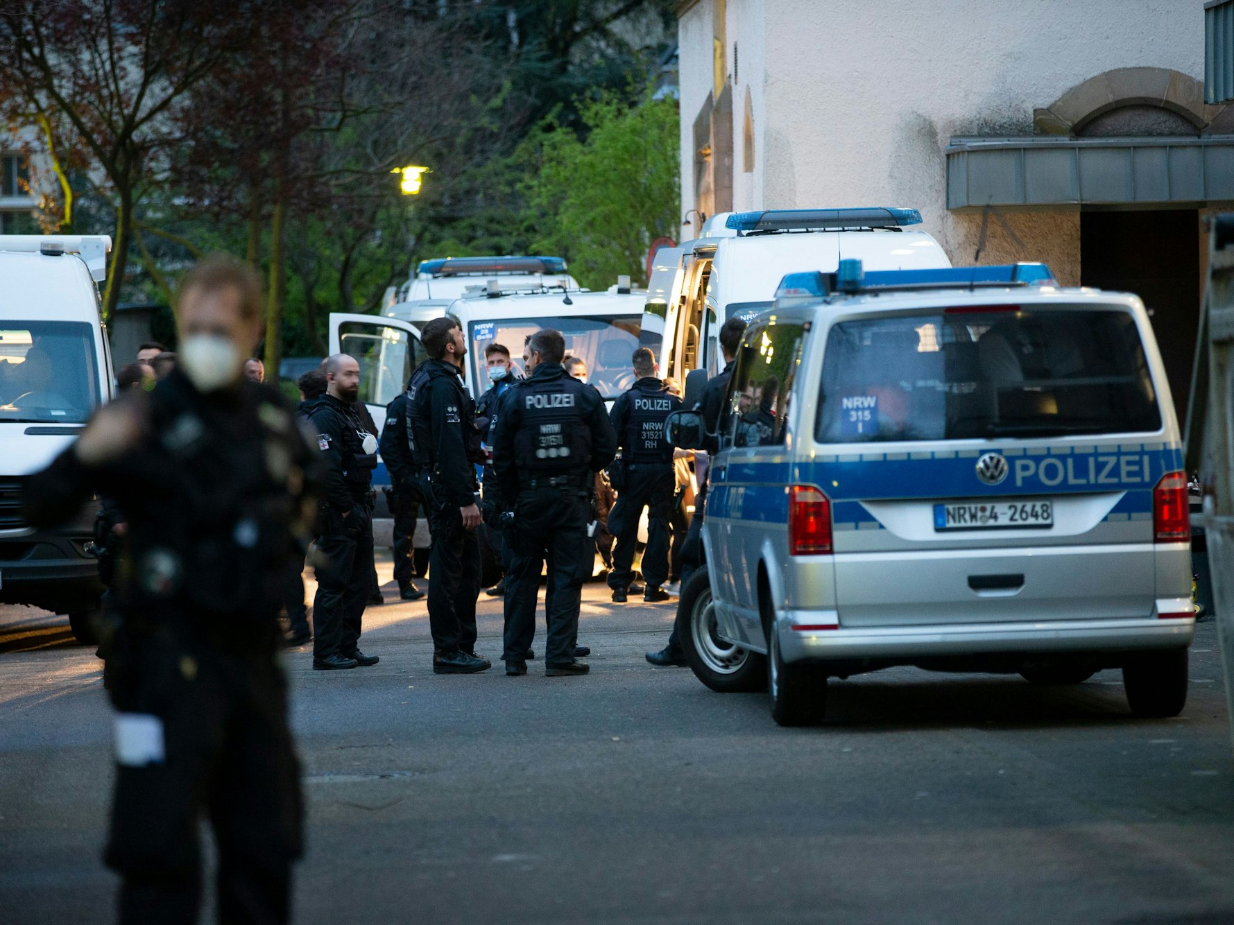 Polizeikräfte stehen vor mehreren Polizeiautos.