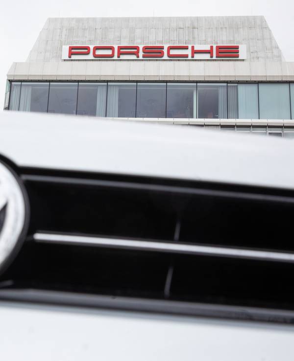 VW-Logo vor Porsche Gebäude.