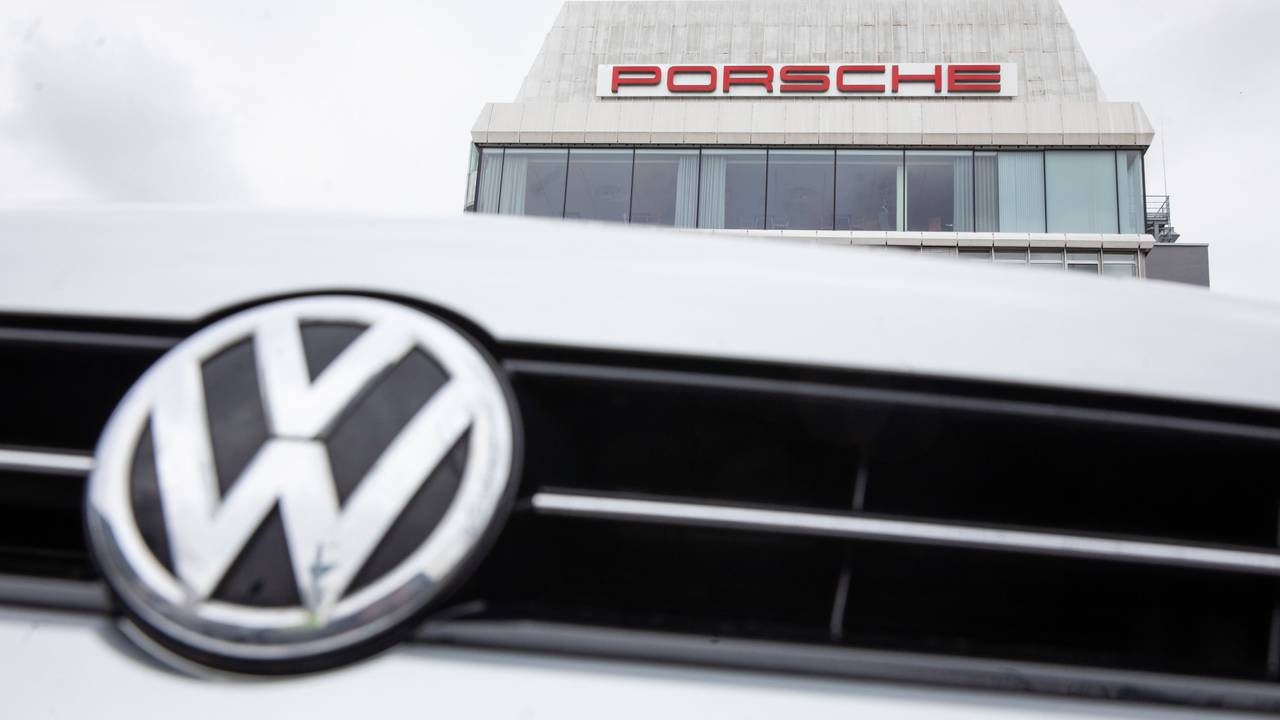 VW-Logo vor Porsche Gebäude.