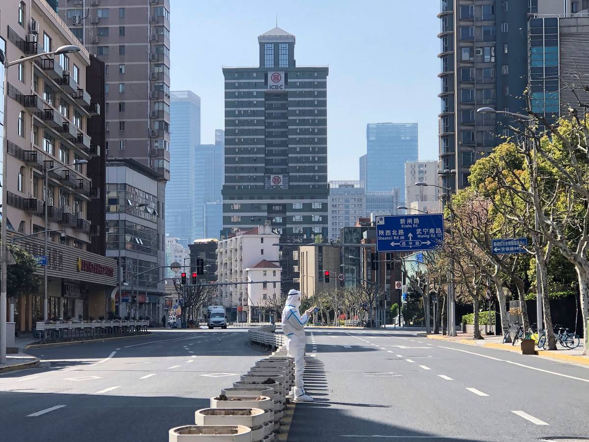 Ein Mann in einem Schutzanzug steht inmitten leerer Straßen in einem abgesperrten Gebiet im Bezirk Jingan im Westen von Shanghai.
