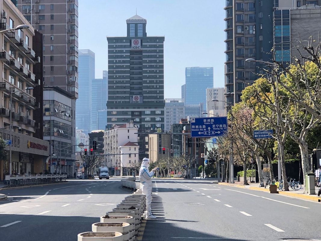Ein Mann in einem Schutzanzug steht inmitten leerer Straßen in einem abgesperrten Gebiet im Bezirk Jingan im Westen von Shanghai.