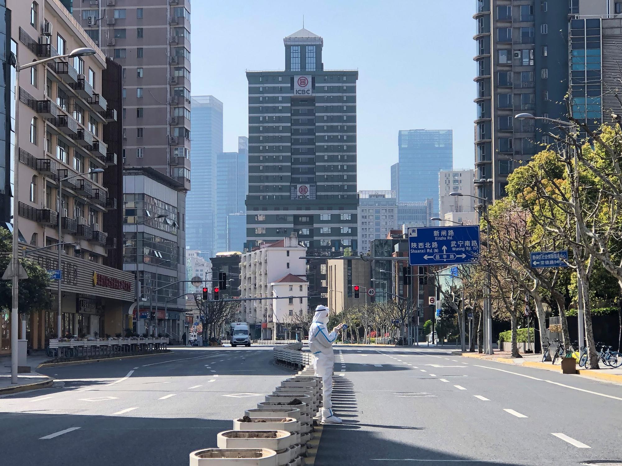 Ein Mann in einem Schutzanzug steht inmitten leerer Straßen in einem abgesperrten Gebiet im Bezirk Jingan im Westen von Shanghai.