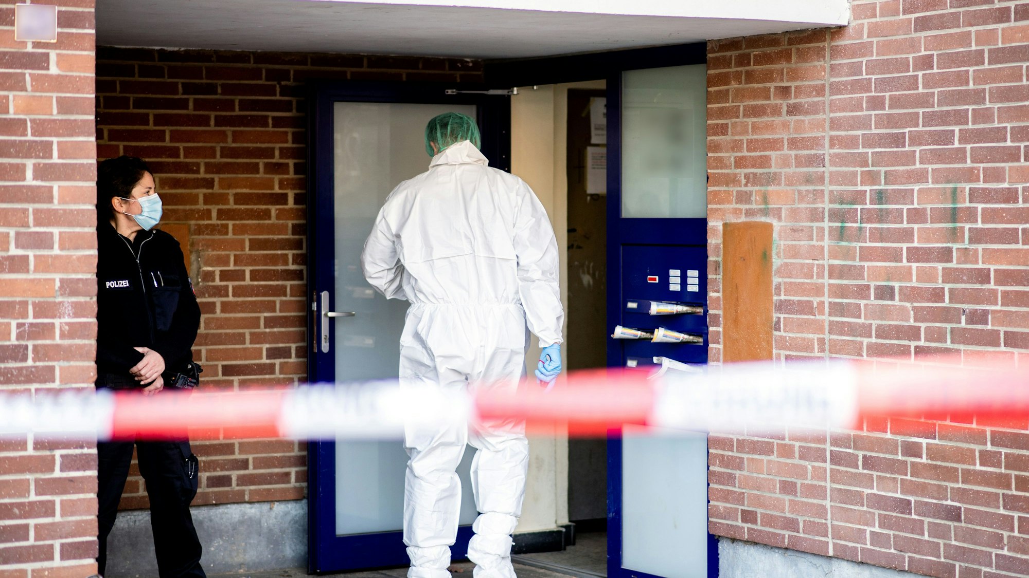 Ein Ermittler der Spurensicherung betritt ein Mehrfamilienhaus.