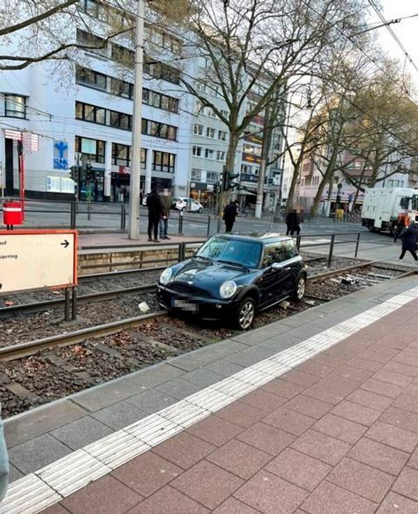 Ein Auto liegt in einem Gleisbett einer Straßenbahnhaltestelle.