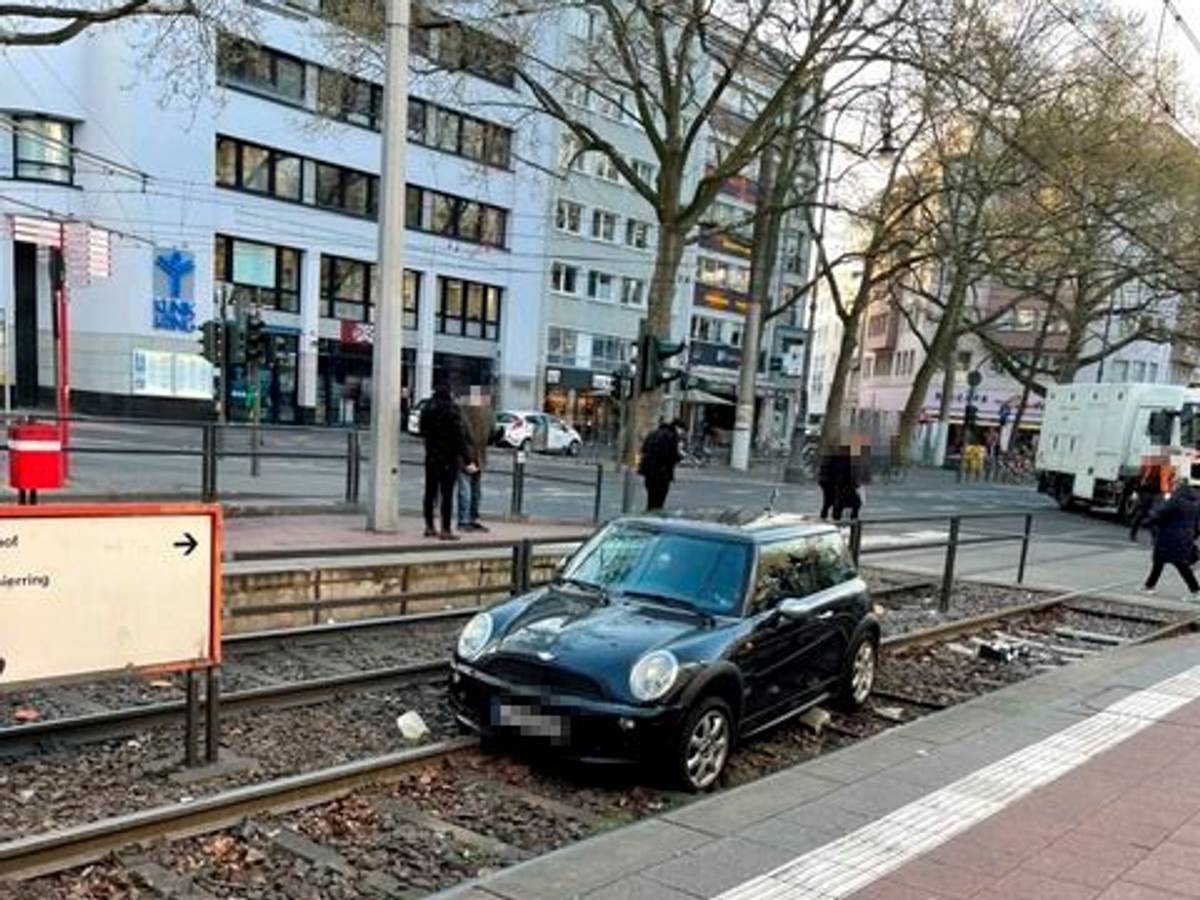 Ein Auto liegt in einem Gleisbett einer Straßenbahnhaltestelle.