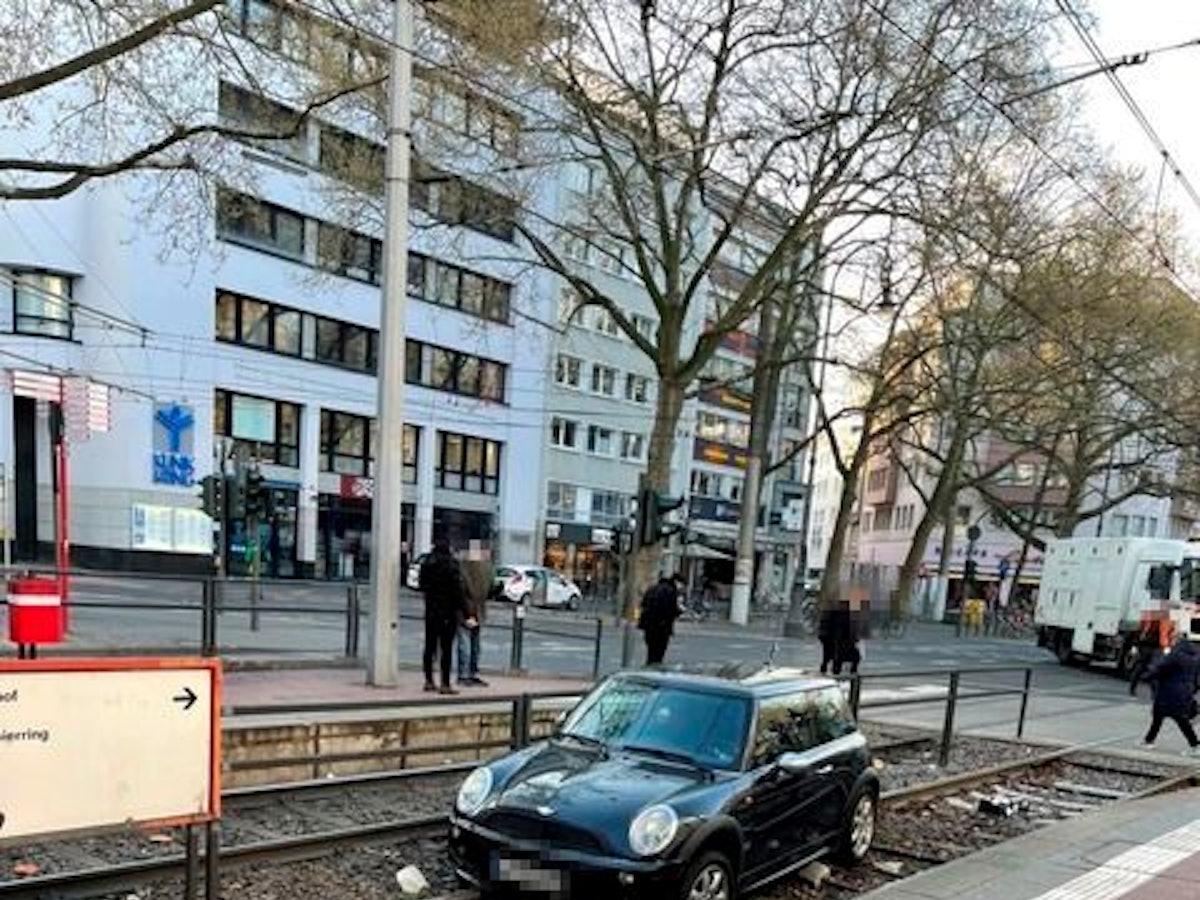 Ein Auto liegt in einem Gleisbett einer Straßenbahnhaltestelle.