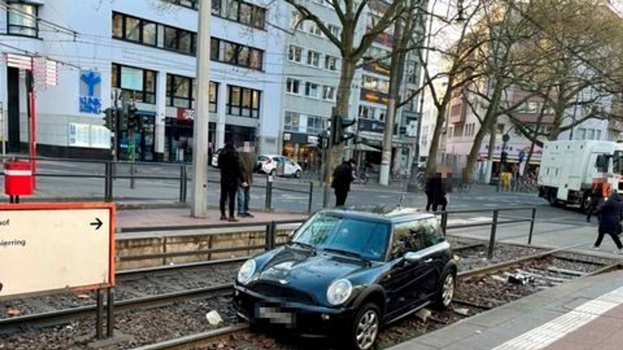 Ein Auto liegt in einem Gleisbett einer Straßenbahnhaltestelle.