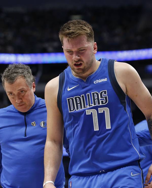 Luka Doncic (Mitte) von den Dallas Mavericks verlässt den Platz nach einer Verletzung in Begleitung von Casey Smith and Moses Wright.