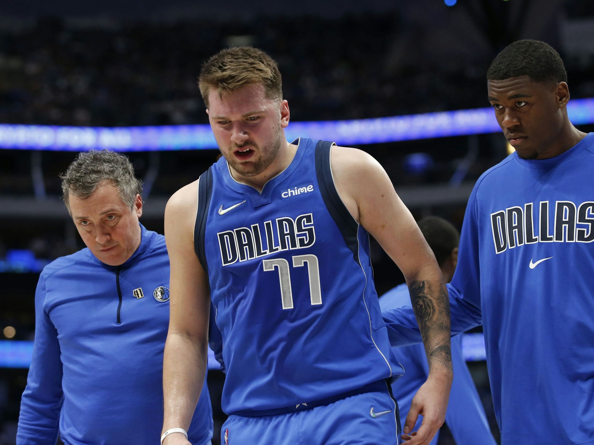 Luka Doncic (Mitte) von den Dallas Mavericks verlässt den Platz nach einer Verletzung in Begleitung von Casey Smith and Moses Wright.