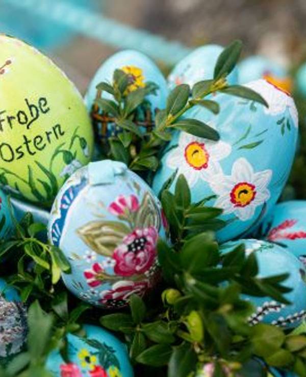 Bunt bemalte Ostereier sind am 10. April 2022 an einem Osterbrunnen angebracht, eines trägt die Aufschrift „Frohe Ostern“.