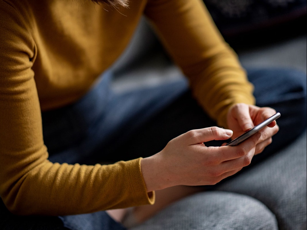 Eine junge Frau hält ein Smartphone in der Hand.