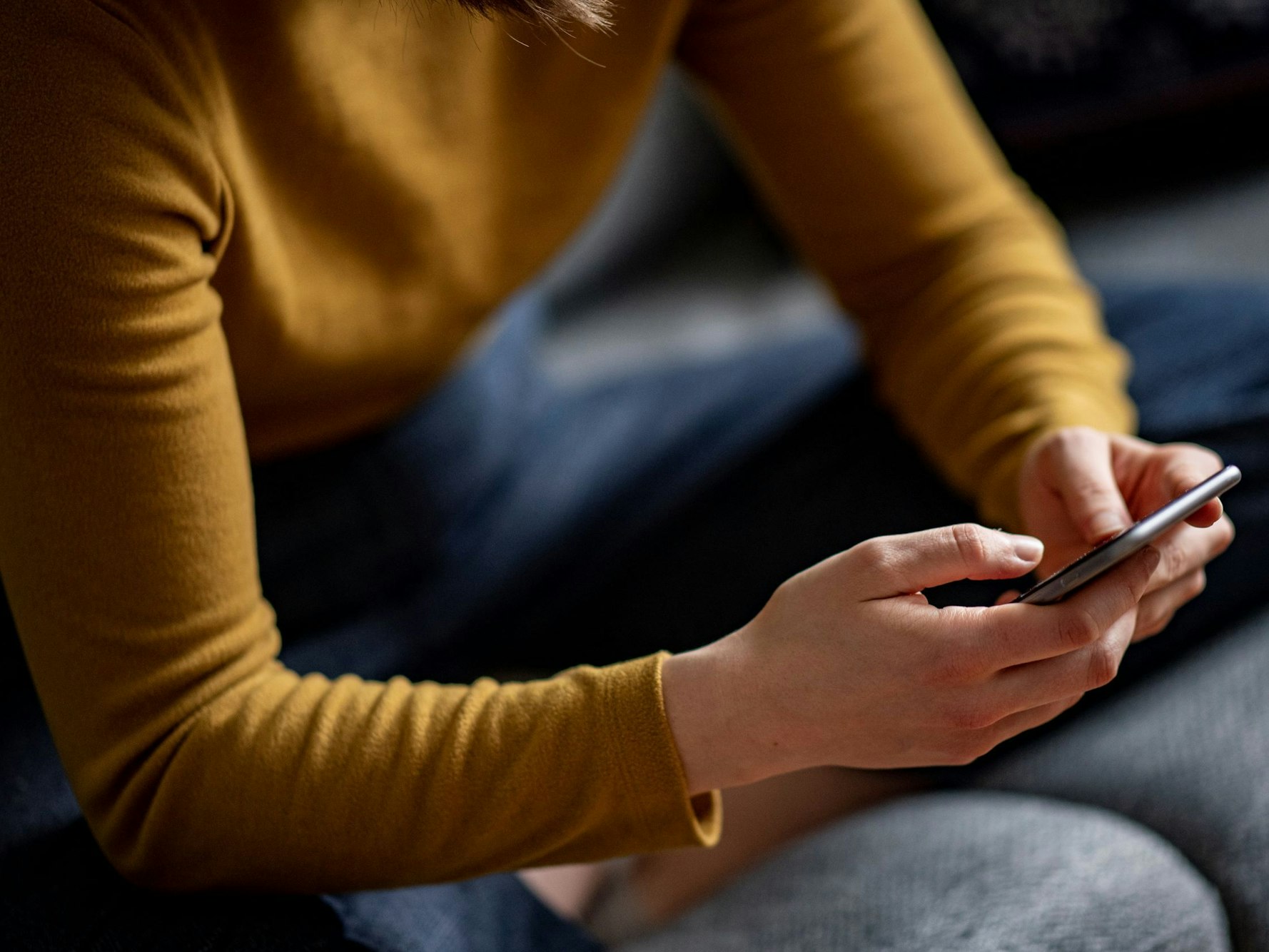 Eine junge Frau hält ein Smartphone in der Hand.