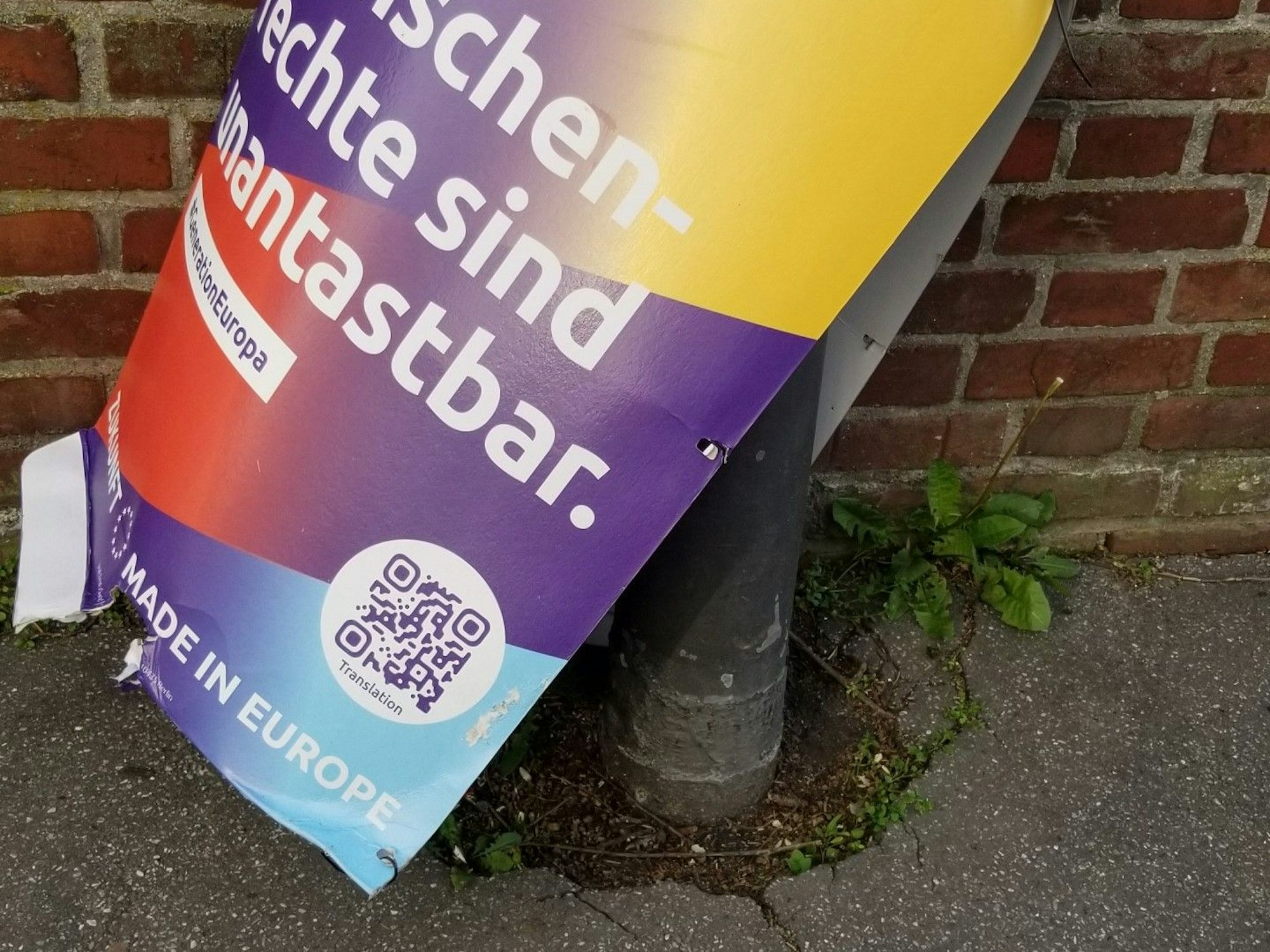Ein abgerissenes Wahlplakat der Volt-Partei ragt in den Fußweg.