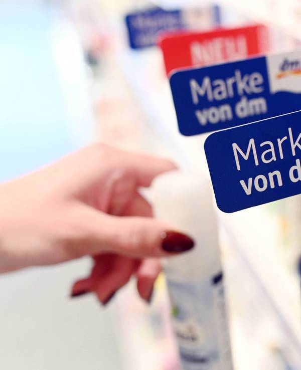 In einem Regal einer Filiale der Drogeriemarktkette dm hängen Schilder, die auf dm Eigenmarken hin weisen. Bei der Aufnahme handelt es sich um ein Symbolfoto von Oktober 2019.