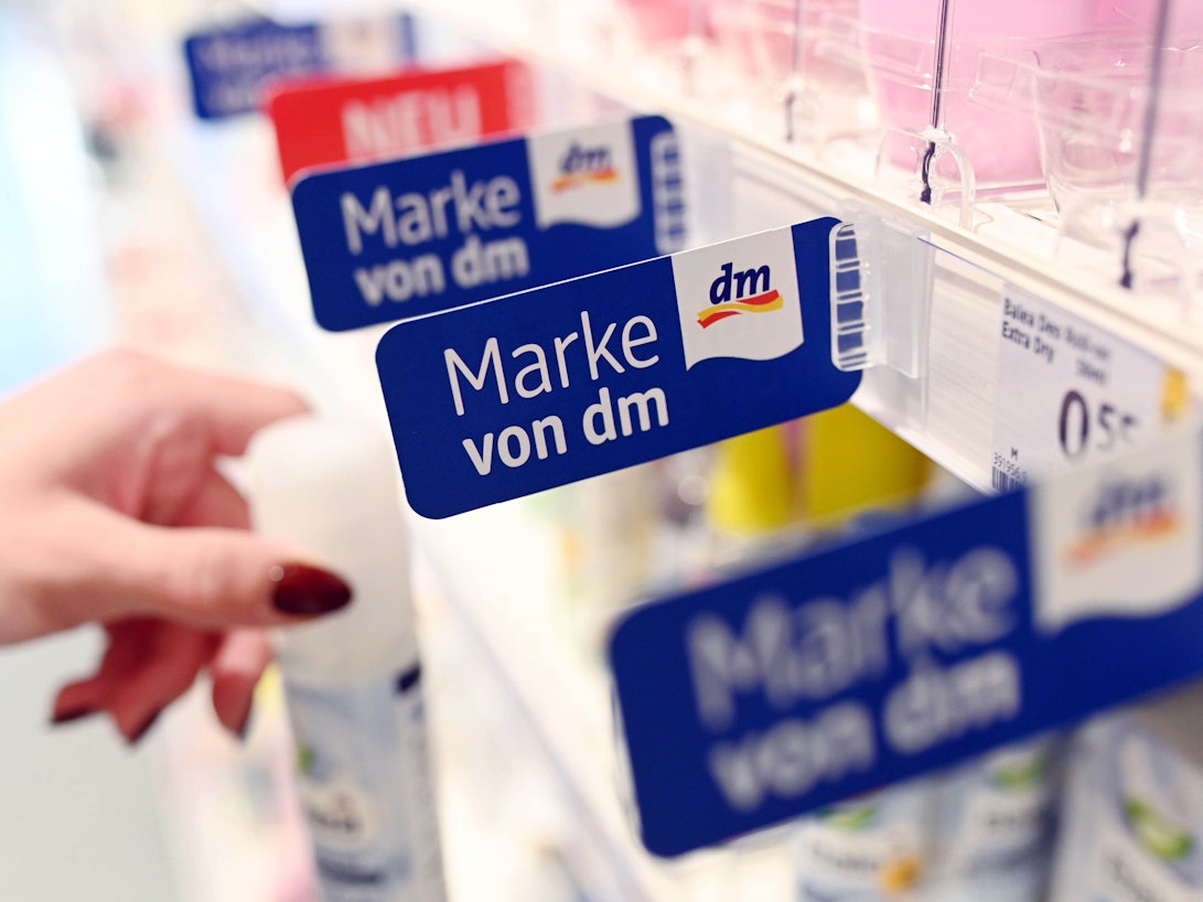 In einem Regal einer Filiale der Drogeriemarktkette dm hängen Schilder, die auf dm Eigenmarken hin weisen. Bei der Aufnahme handelt es sich um ein Symbolfoto von Oktober 2019.