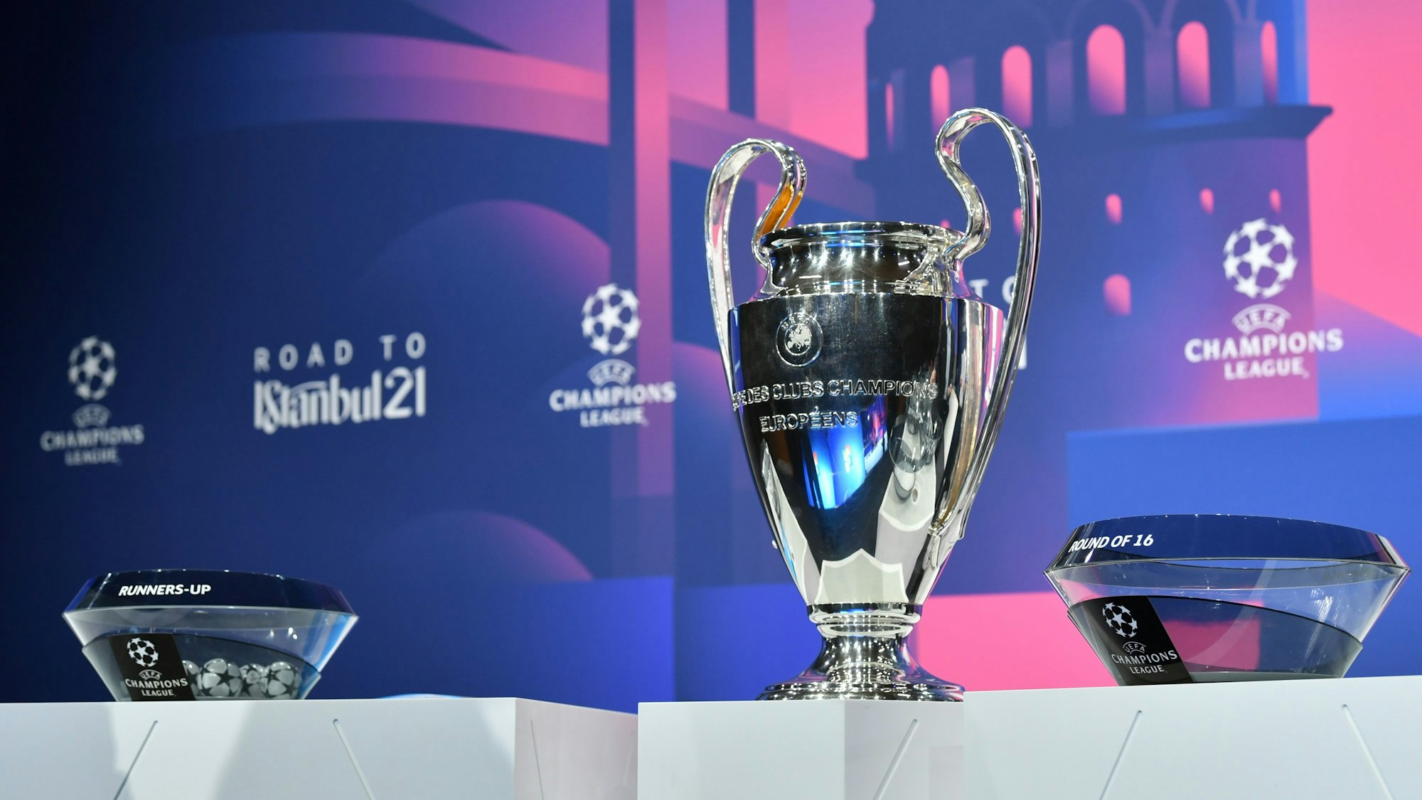 Fußball: UEFA Champions League, Auslosung - K.o.-Runde, Achtelfinale. Der Champions-League-Pokal steht neben den Lostöpfen auf einem Podest.