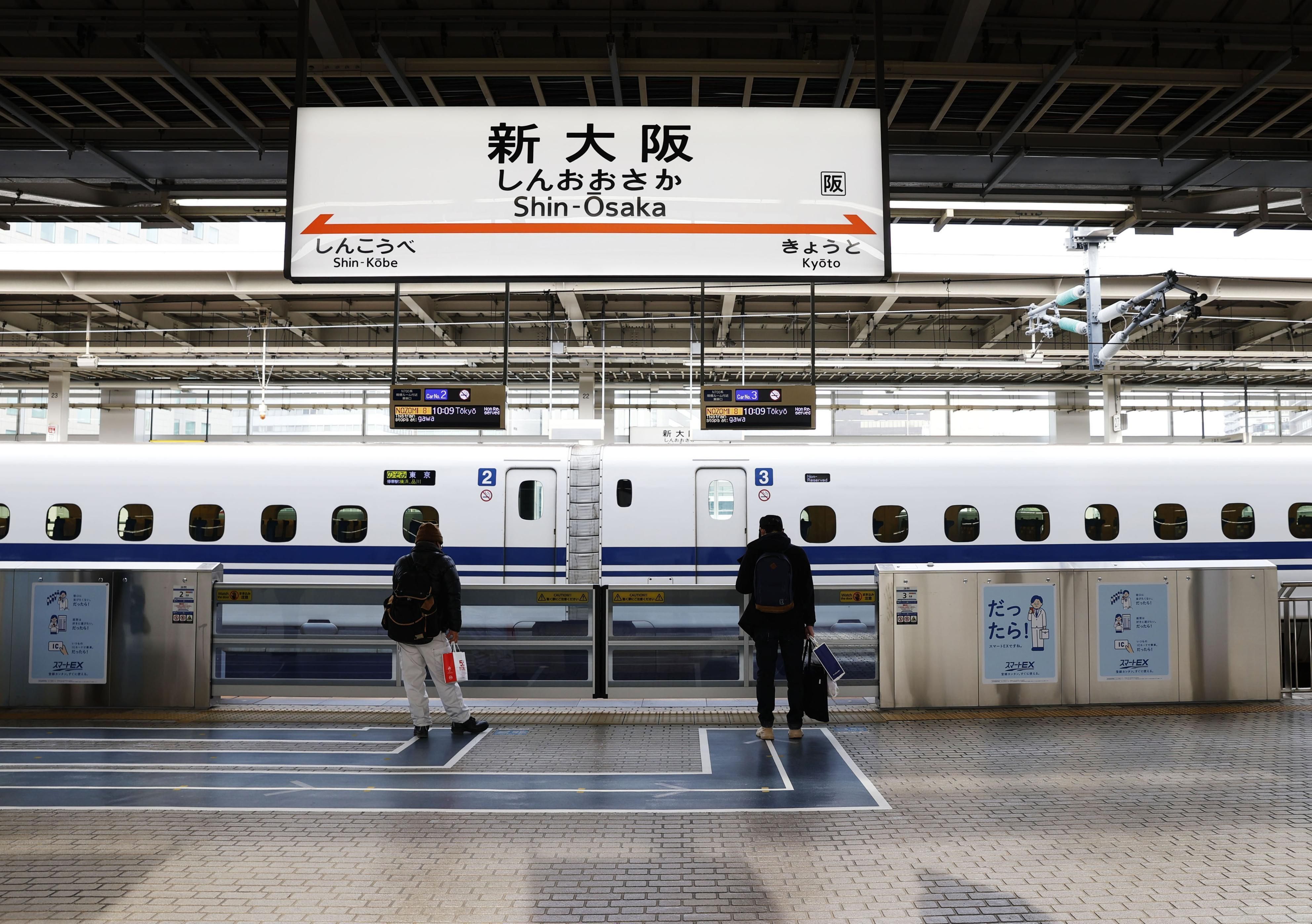 Zwei Reisende stehen an einem Bahnsteig der japanischen Hochgeschwindigkeitszüge am 3. Januar 2021 am Bahnhof Shin-Osaka