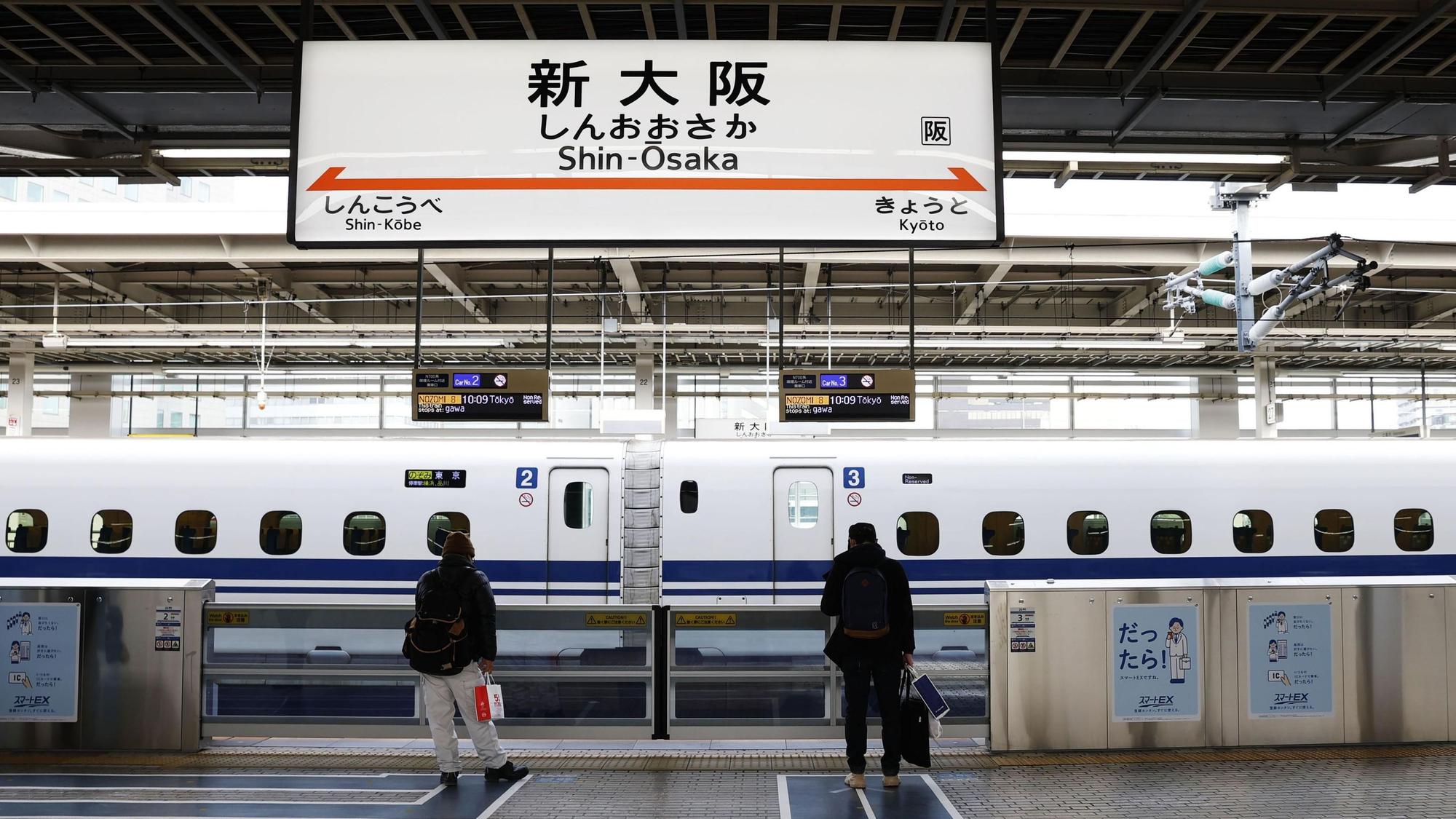 Zwei Reisende stehen an einem Bahnsteig der japanischen Hochgeschwindigkeitszüge am 3. Januar 2021 am Bahnhof Shin-Osaka