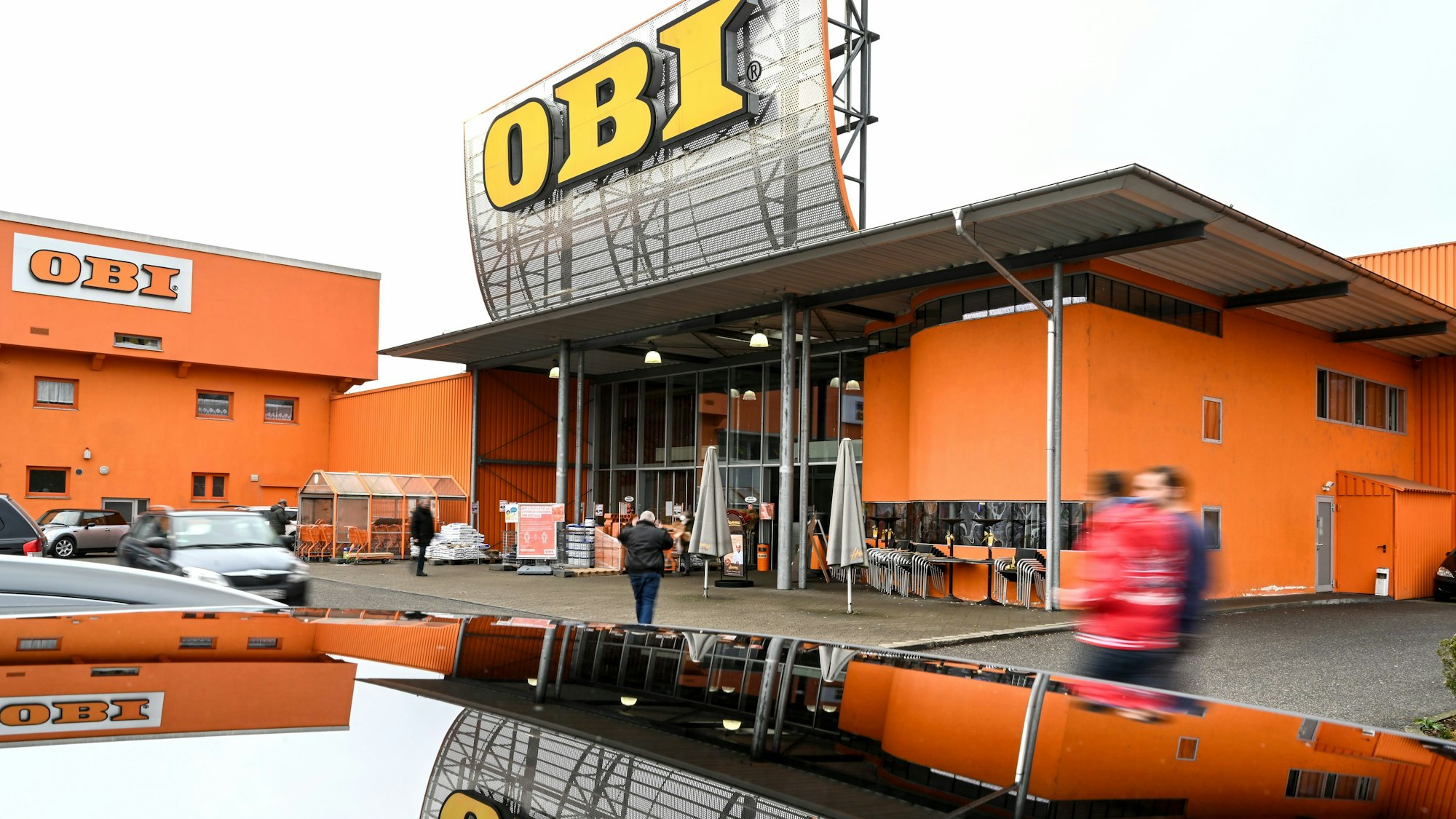 Kundinnen und Kunden gehen auf den Baumarkt Obi zu. Die Baumarkt-Kette Obi gibt ihre 27 russischen Baumärkte ab.