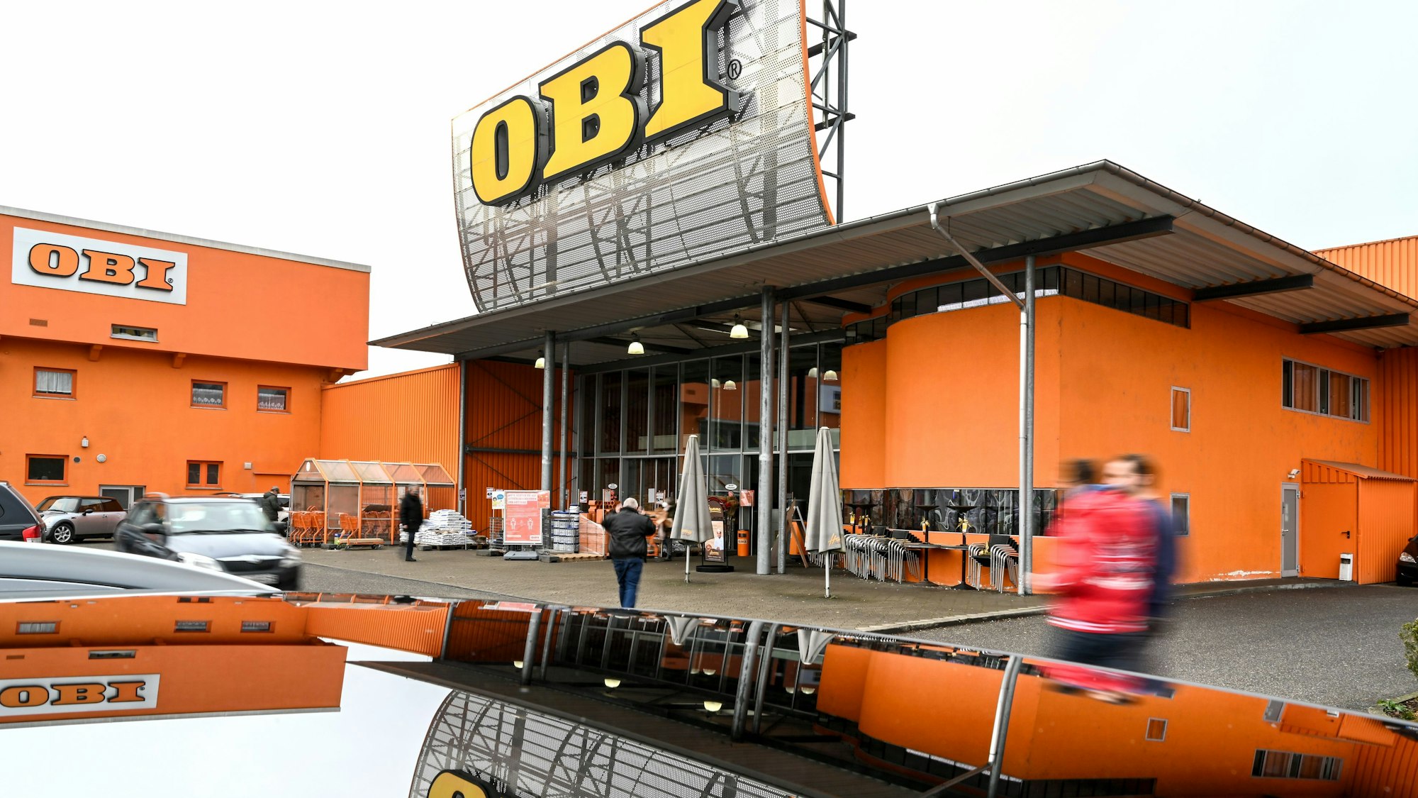 Kundinnen und Kunden gehen auf den Baumarkt Obi zu. Die Baumarkt-Kette Obi gibt ihre 27 russischen Baumärkte ab.
