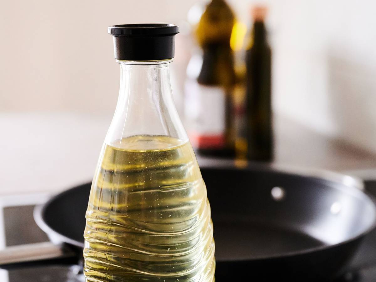 In eine Glasflasche abgefülltes Sonnenblumenöl steht neben einer Pfanne in einer Küche. Die Nachfrage nach Speiseöl und Mehl in Deutschland ist nach Beginn des Ukraine-Krieges zeitweise stark gestiegen.