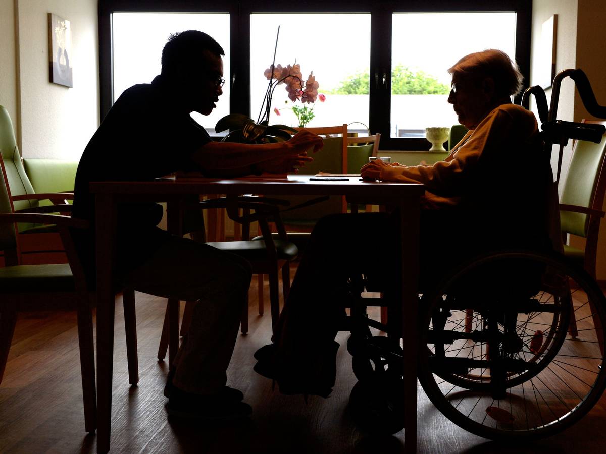 Ein Azubi zum Altenpfleger unterhält sich im Pflegeheim Eilenriedestift in Hannover mit einer Seniorin.