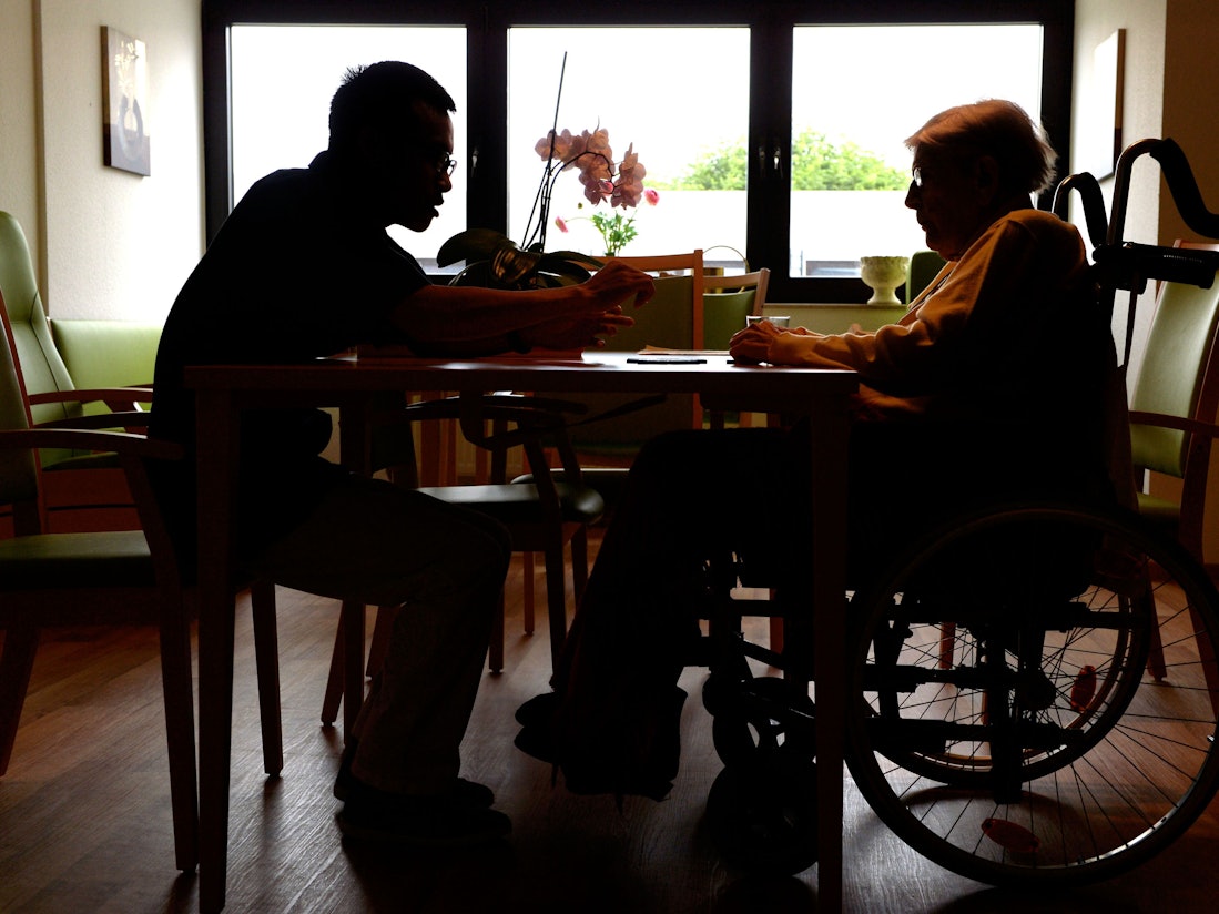 Ein Azubi zum Altenpfleger unterhält sich im Pflegeheim Eilenriedestift in Hannover mit einer Seniorin.