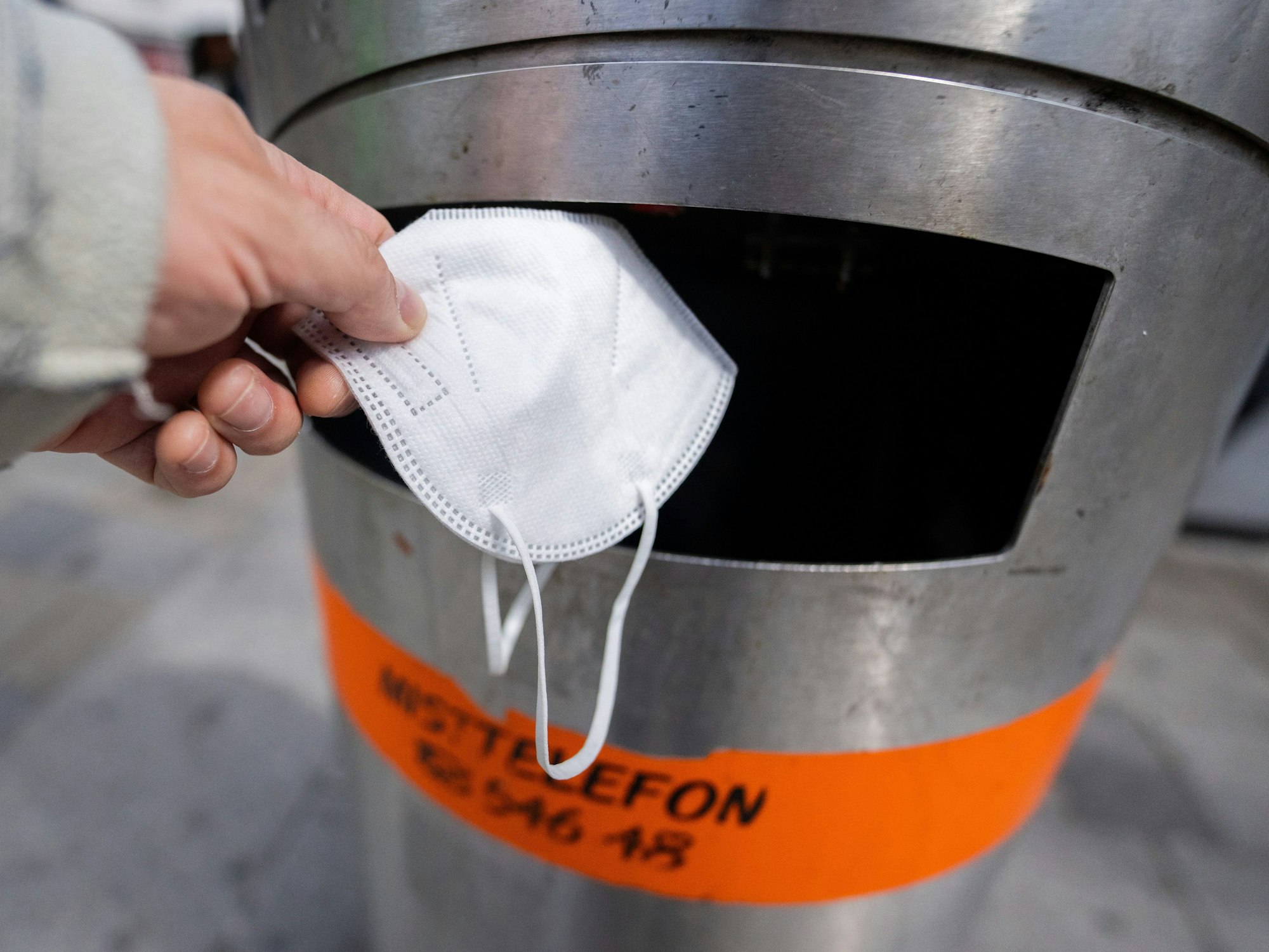 Eine FFP2-Maske wird in einen Abfalleimer geworfen.