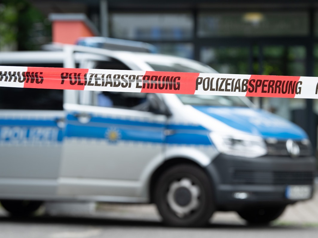 Ein Polizeiauto steht hinter einer Absperrung.