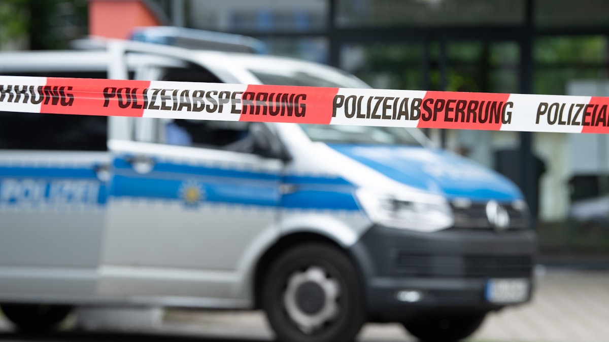 Ein Polizeiauto steht hinter einer Absperrung.